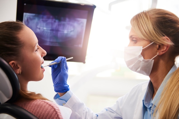 Vrouwelijke orthodontist die tandspiegel gebruikt tijdens controle