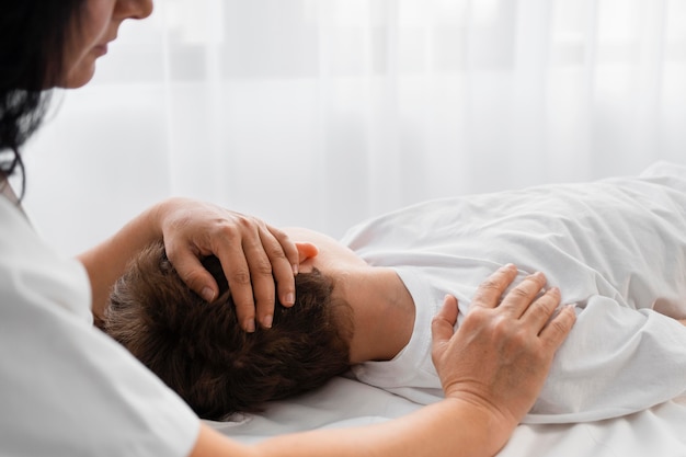 Vrouwelijke osteopaat die een jongen behandelt door hem te masseren
