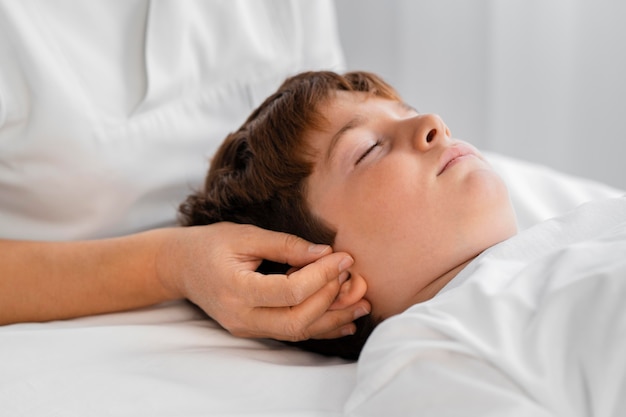 Vrouwelijke osteopaat die een kind behandelt door zijn hoofd te masseren