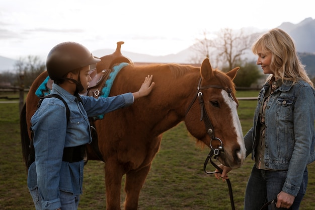 Gratis foto vrouwelijke paardensportinstructeur die kind leert paardrijden