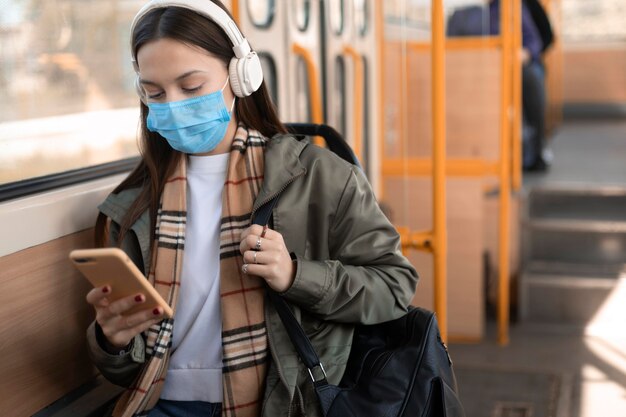 Vrouwelijke passagier die medisch masker draagt en aan muziek luistert