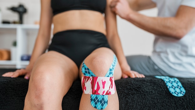 Gratis foto vrouwelijke patiënt bij fysiotherapie met kniebrace tape