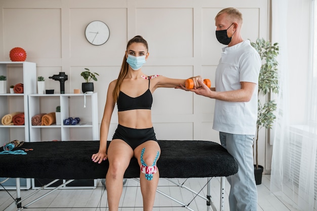 Gratis foto vrouwelijke patiënt bij fysiotherapie met man en halter