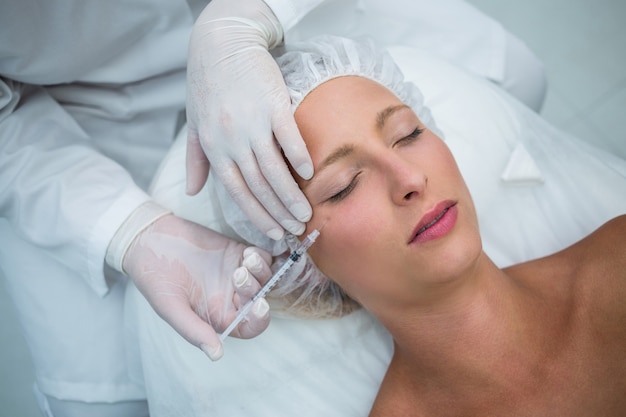 Vrouwelijke patiënt die een botoxinjectie op gezicht ontvangt