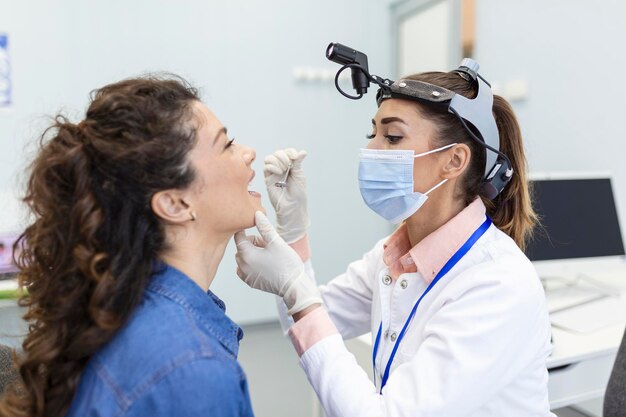 Vrouwelijke patiënt die haar mond opent zodat de dokter in haar keel kan kijken Otolaryngoloog onderzoekt keelpijn van patiënt