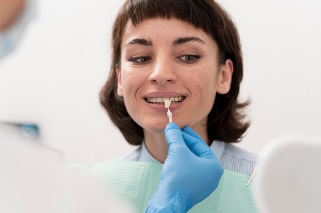 Vrouwelijke patiënt die in de spiegel kijkt op het kantoor van de tandarts
