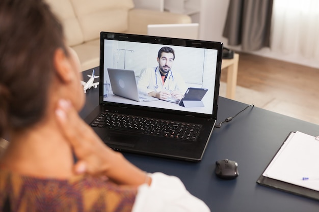 Vrouwelijke patiënt in een videogesprek met arts die praat over haar nekletsel.