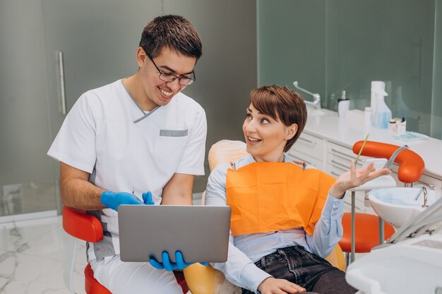 Vrouwelijke patiënt zittend in een tandartsstoel en professinal hygiëne maken