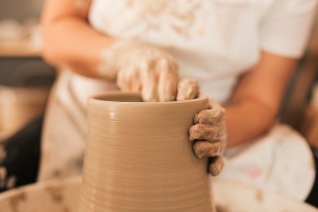 Vrouwelijke pottenbakker die aan aardewerkwiel werkt