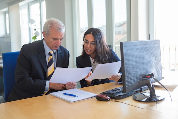 Vrouwelijke professional document details uit te leggen aan de klant op de werkplek. Serieuze bedrijfsleider die een financieel of juridisch expert raadpleegt. Teamwork of samenwerking concept