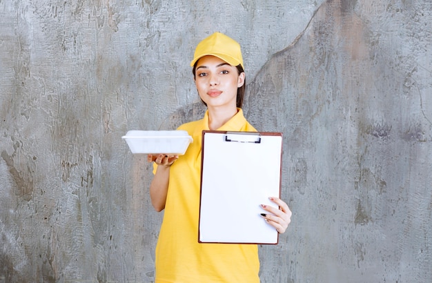 Vrouwelijke serviceagent in geel uniform die een plastic afhaaldoos vasthoudt en om een handtekening vraagt.