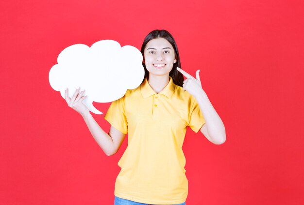 Vrouwelijke servicemedewerker die een infobalie in de vorm van een wolk vasthoudt en zich positief voelt