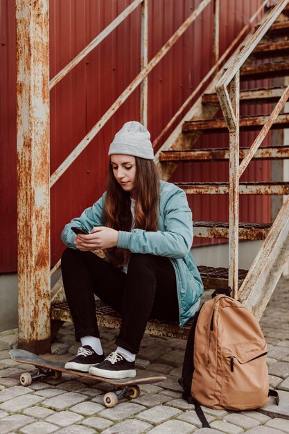 Vrouwelijke skater zit naast haar skateboarden buitenshuis