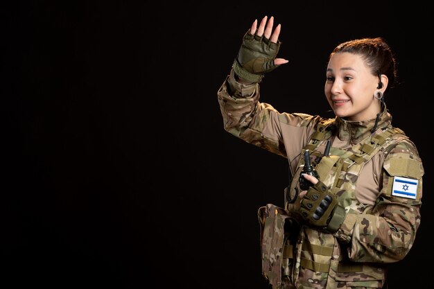 Vrouwelijke soldaat in camouflage met granaat op de zwarte muur