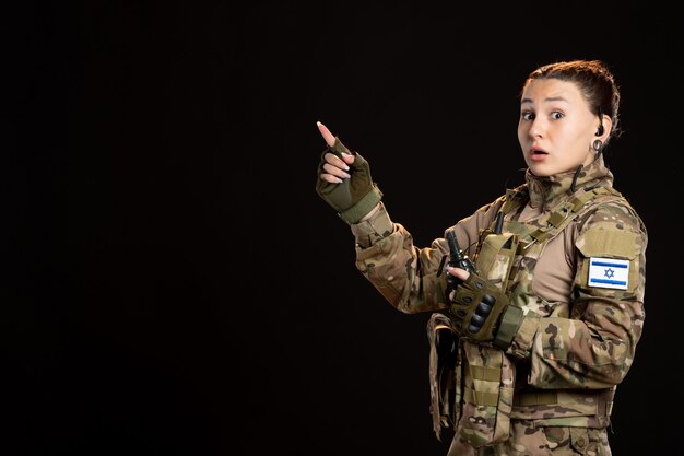 Vrouwelijke soldaat in camouflage met granaat op de zwarte muur