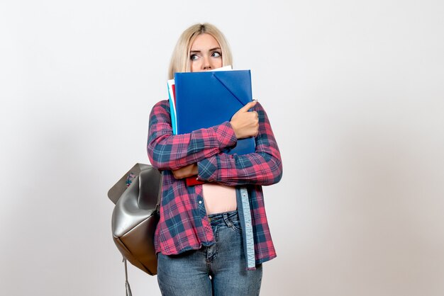 vrouwelijke student die verschillende bestanden op witte vloer school student bibliotheek meisje lessen college