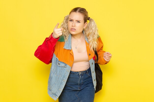 vrouwelijke student jong in moderne kleding dreigt op geel