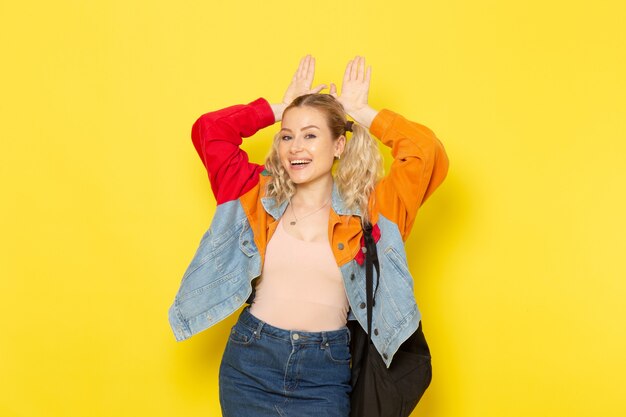 vrouwelijke student jong in moderne kleding gewoon poseren met een glimlach op geel