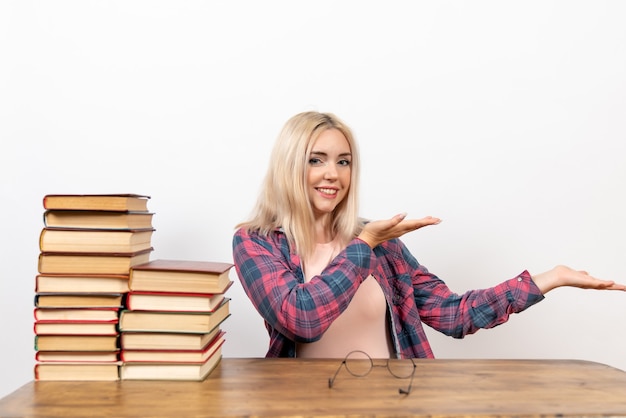 Vrouwelijke student zit gewoon met boeken lachend op wit