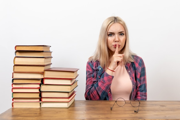 Gratis foto vrouwelijke student zit gewoon met boeken op wit