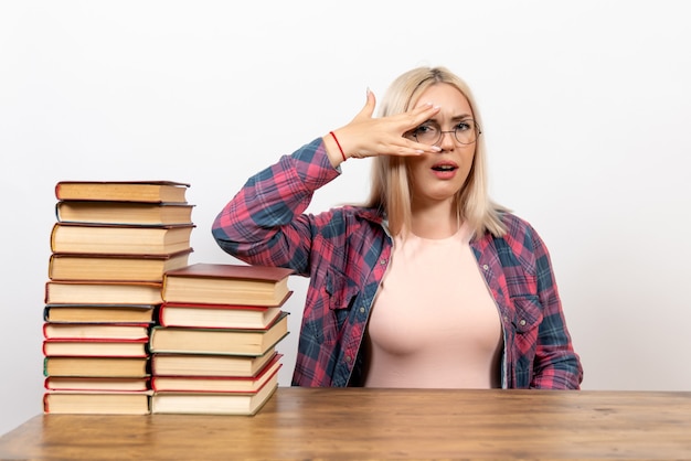 Vrouwelijke student zit gewoon met boeken op wit