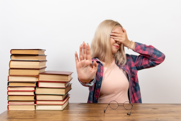 Gratis foto vrouwelijke student zit gewoon met boeken over licht wit