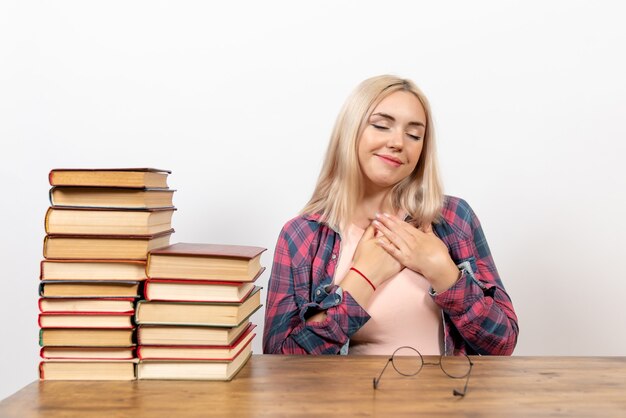 vrouwelijke student zit gewoon met boeken over licht wit