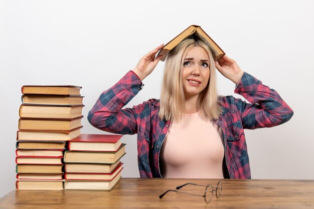 vrouwelijke student zit met boeken op wit