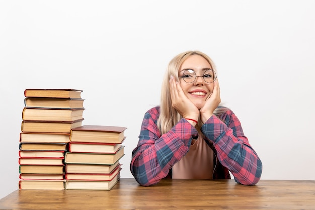 vrouwelijke student zit met verschillende boeken op wit