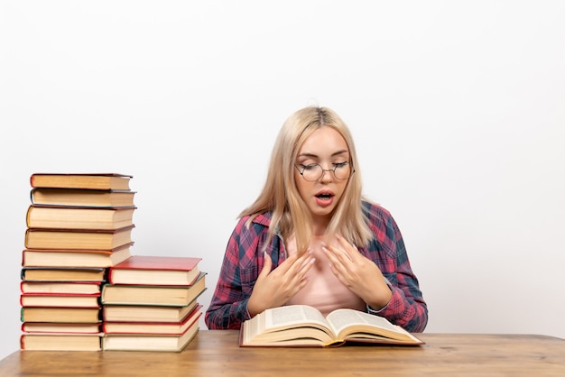 vrouwelijke student zitten met boeken en lezen op wit
