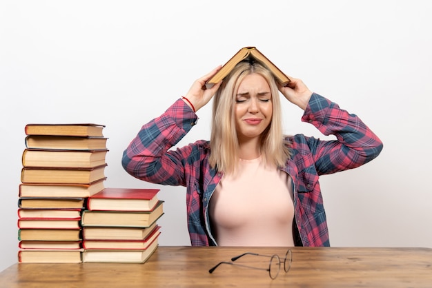 vrouwelijke student zitten met boeken en lezen op wit