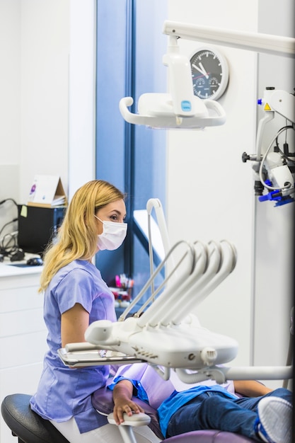 Vrouwelijke tandarts die chirurgisch masker in kliniek draagt