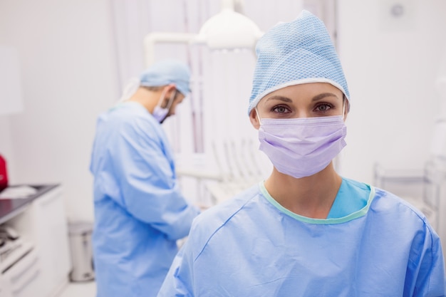 Vrouwelijke tandarts die en bij tandkliniek glimlachen stellen