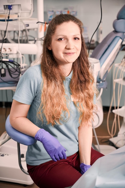 Gratis foto vrouwelijke tandarts zittend op stoel in stomatologie kabinet