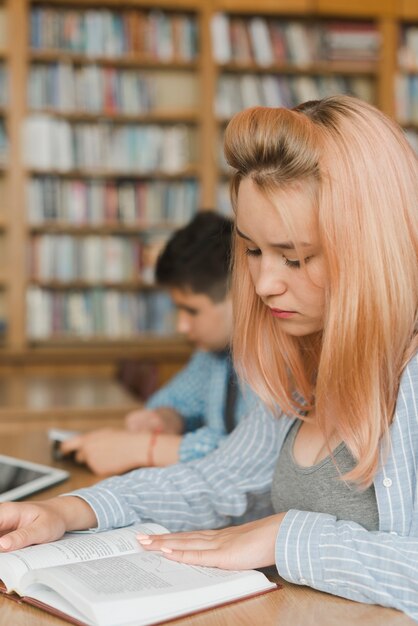 Vrouwelijke tiener die in bibliotheek bestudeert