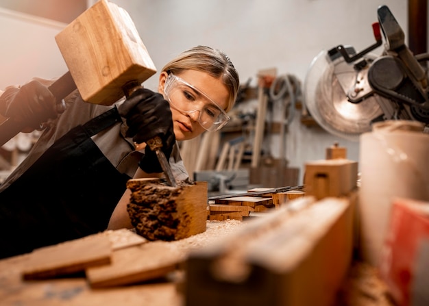 Vrouwelijke timmerman in de studio met hulpmiddelen voor het beeldhouwen van hout
