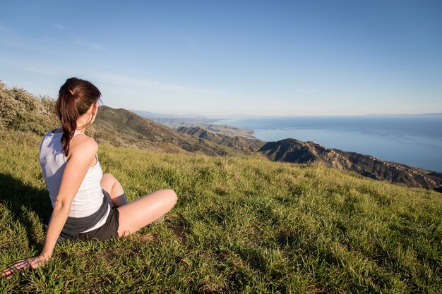 Vrouwelijke toeristenzitting bovenop de Gaviota Peak-wandelingssleep die de Kust van Californië overzien