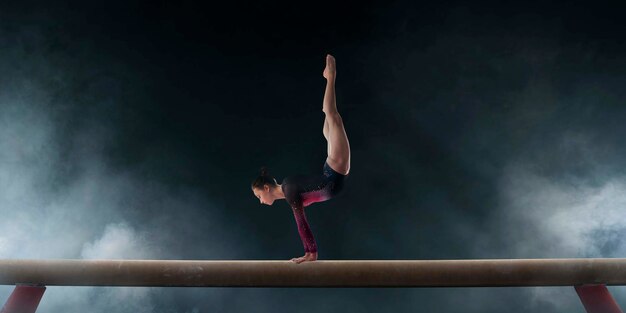 Gratis foto vrouwelijke turnster doet een ingewikkelde truc op gymnastiek-evenwichtsbalk in een professionele arena
