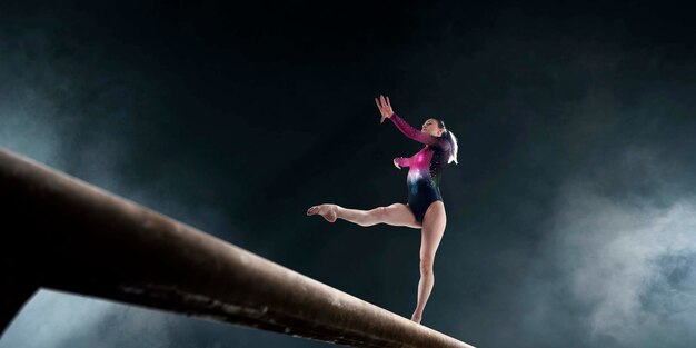 Vrouwelijke turnster doet een ingewikkelde truc op gymnastiek-evenwichtsbalk in een professionele arena