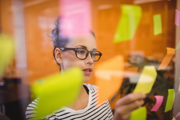 Vrouwelijke uitvoerende lezen sticky notes