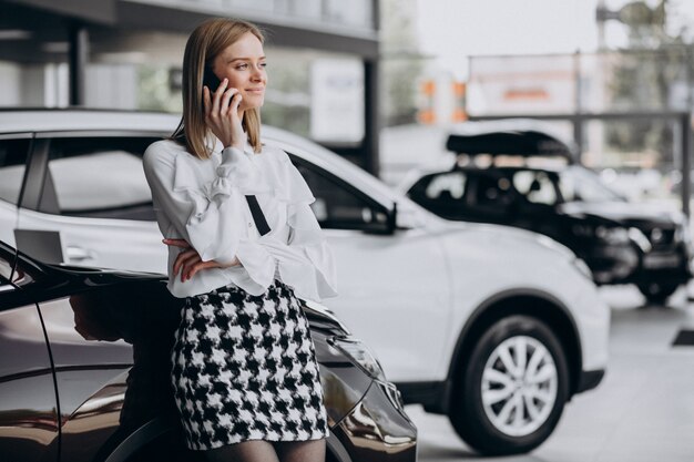 Vrouwelijke verkoper bij een autoshowroom die zich door de auto bevindt