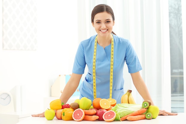 Vrouwelijke voedingsdeskundige met verschillende groenten en fruit aan de balie