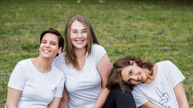 Vrouwelijke vrienden die bij gras het glimlachen zitten