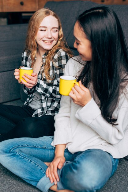 Vrouwelijke vrienden die en thee spreken drinken