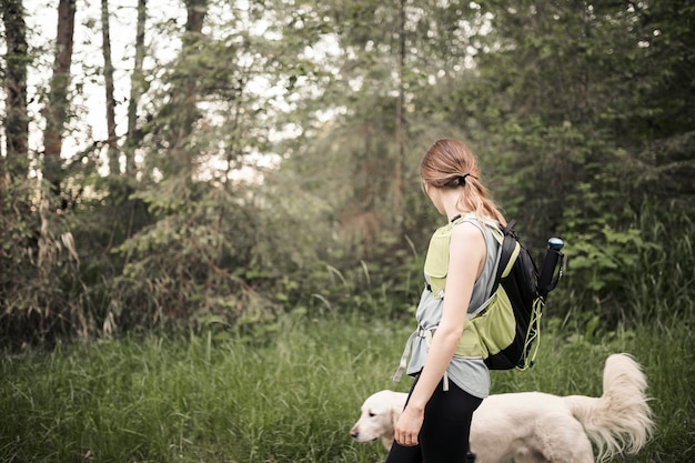 Vrouwelijke wandelaar met haar hond die in het bos loopt