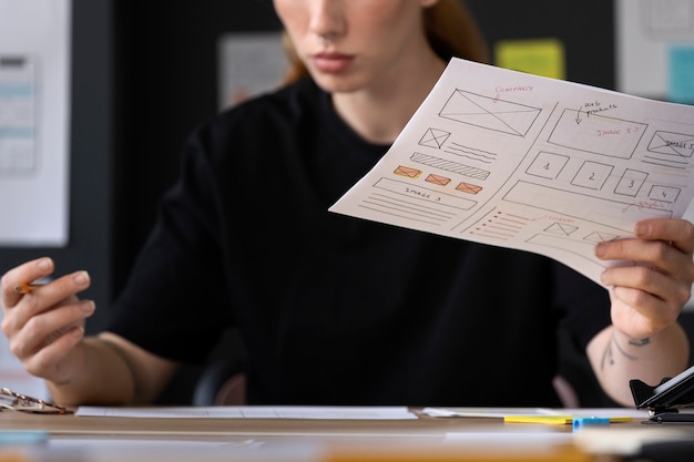 Vrouwelijke webdesigner met papieren en notities op kantoor