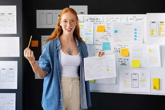 Vrouwelijke webdesigner met papieren en notities op kantoor