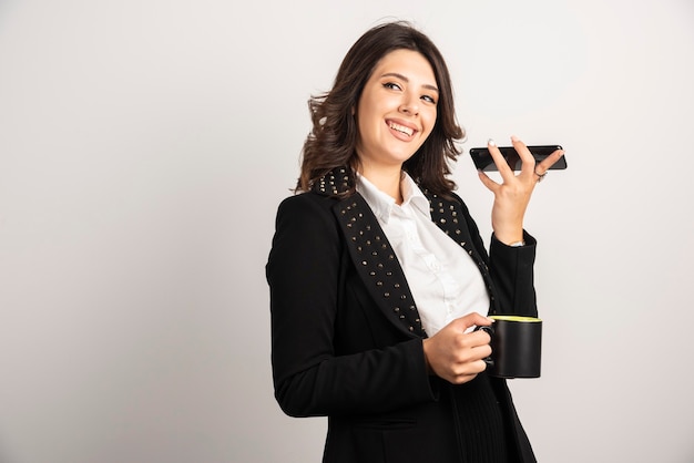 Vrouwelijke werknemer met kopje thee en telefoon