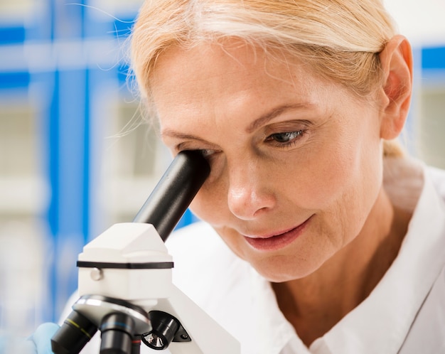 Vrouwelijke wetenschapper die door microscoop kijkt