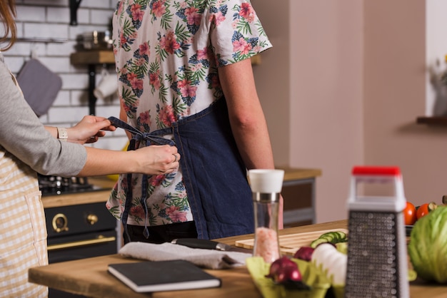 Gratis foto vrouwen bindende schort op de mens in keuken